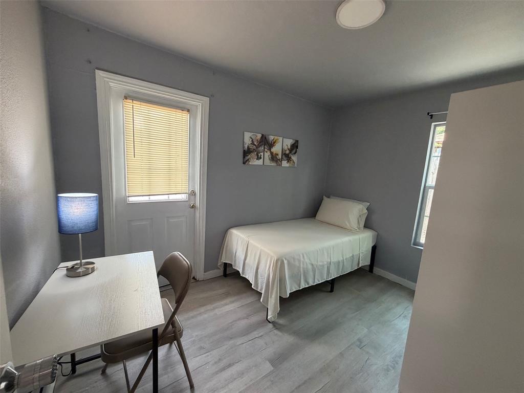 714 Southwest Dallas Street Grand Prairie, TX 75051 - Photo 10 of 27 Room featuring light gray walls, wood-finish flooring, and a white paneled door with integrated blinds