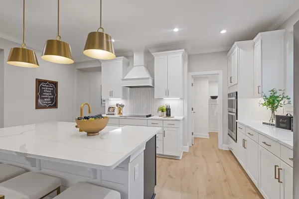 a kitchen with stainless steel appliances a sink a stove a refrigerator a center island a stove and white cabinets