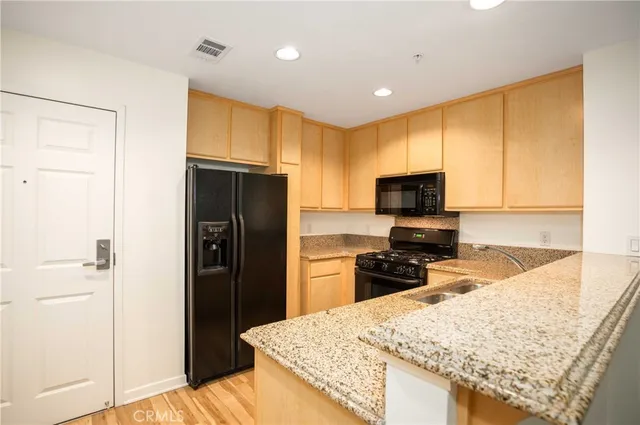 a kitchen with granite countertop wooden cabinets a refrigerator and a sink