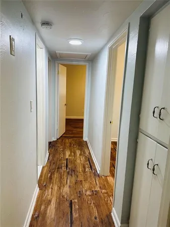 a view of a hallway with wooden floor and bathroom