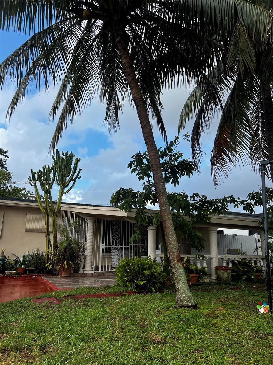 629 Southwest 4th Street Hallandale Beach, FL 33009 - Photo 3 of 4 a front view of a house with a garden and a yard