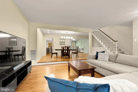 a living room with couches and a dining table with wooden floor