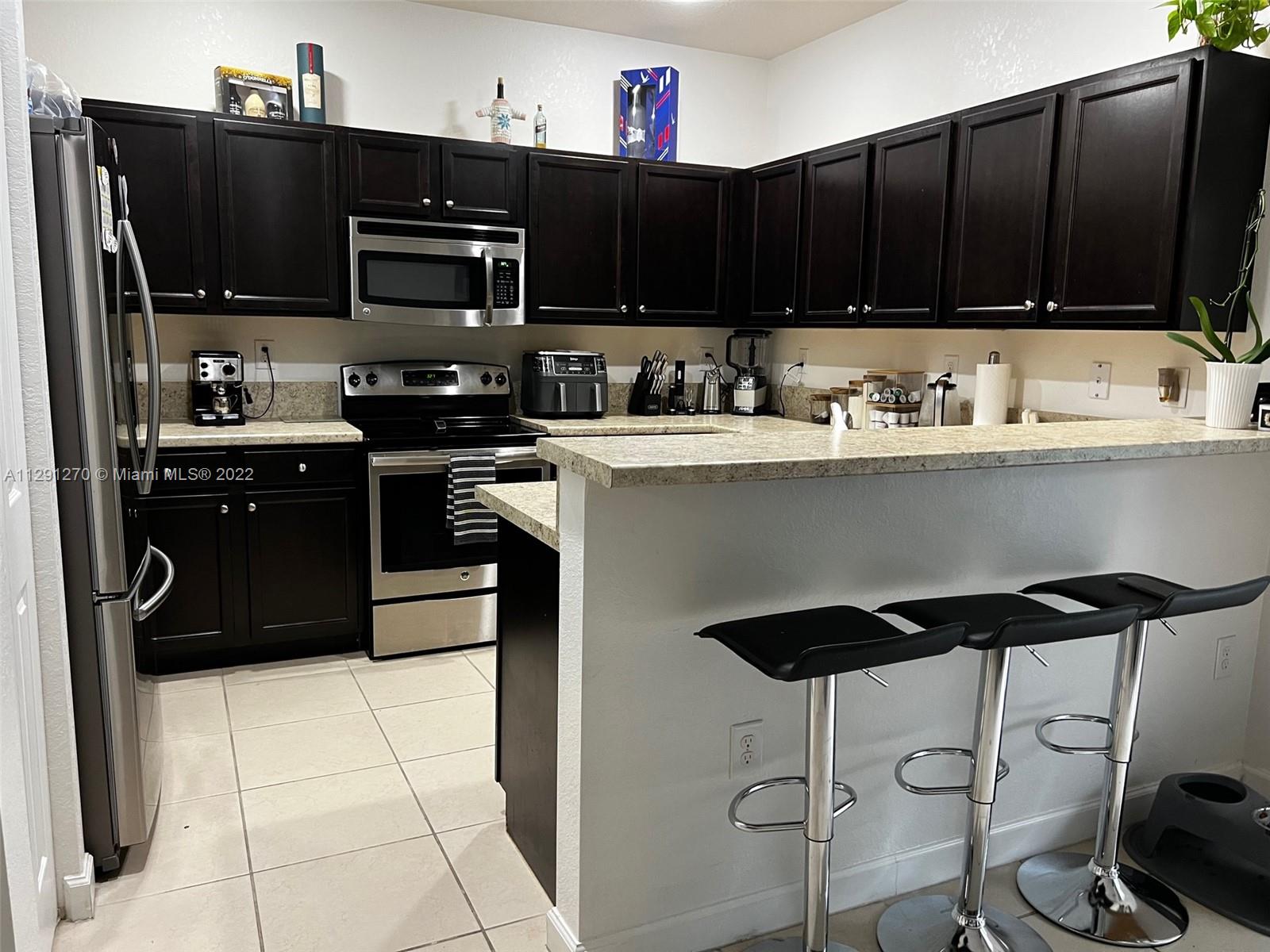 Oasis Homestead, FL 33033 - Photo 15 of 24 a kitchen with stainless steel appliances granite countertop a stove top oven a sink a refrigerator and a microwave
