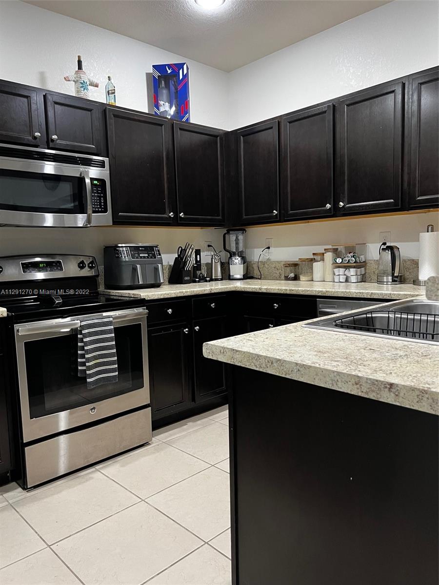 Oasis Homestead, FL 33033 - Photo 16 of 24 a kitchen with granite countertop a stove top oven microwave and cabinets