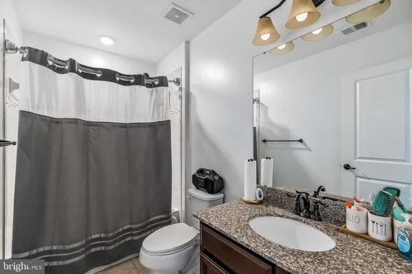 a bathroom with a granite countertop sink toilet a mirror a vanity and shower