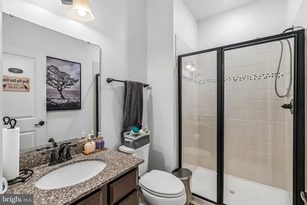 a bathroom with a granite countertop sink toilet a mirror and shower