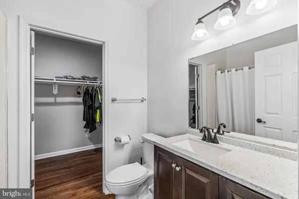 a bathroom with a granite countertop sink toilet and mirror
