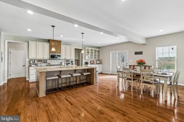 a kitchen with a table chairs wooden floors and a view of living room