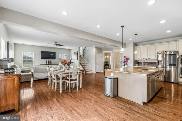 a kitchen with stainless steel appliances a dining table chairs stove refrigerator and cabinets