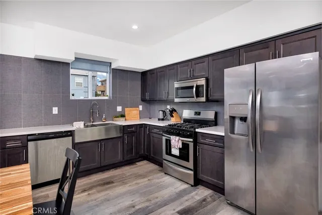 a kitchen with stainless steel appliances granite countertop a refrigerator a sink dishwasher a stove top oven a refrigerator with island and chairs