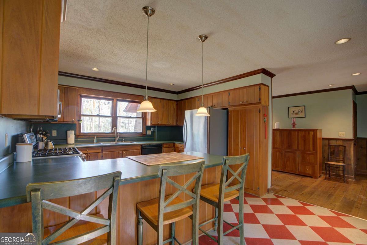 1043 Wilkerson Road Southwest Rome, GA 30165 - Photo 30 of 52 a kitchen with stainless steel appliances granite countertop a stove a refrigerator a dining table and chairs with wooden floor