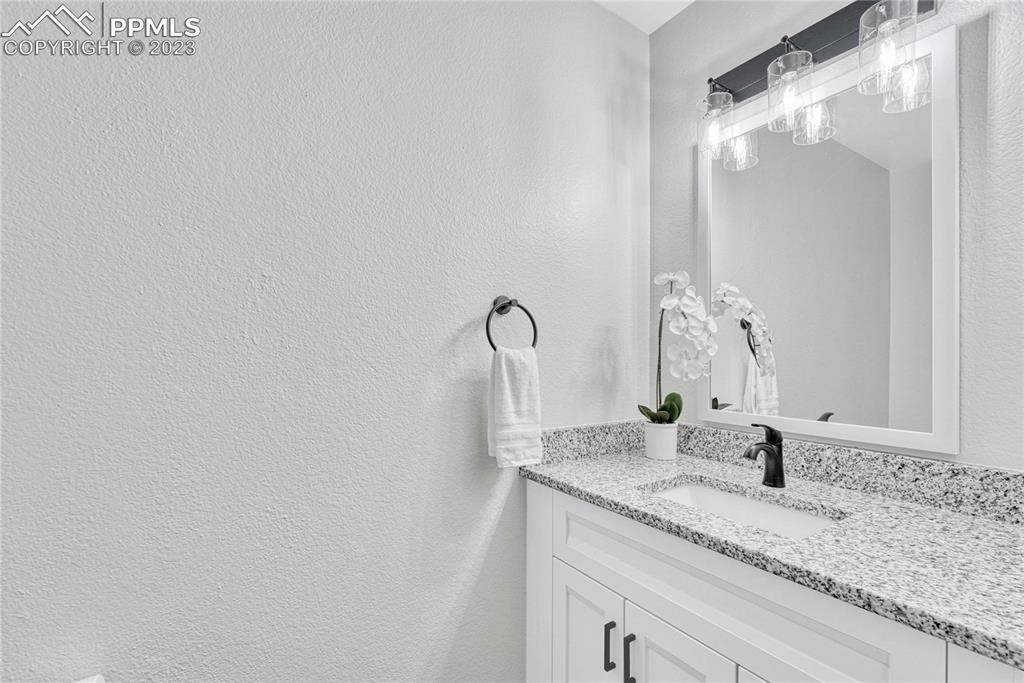 1185 Bowstring Road Monument, CO 80132 - Photo 19 of 46 a bathroom with a granite countertop sink and a mirror