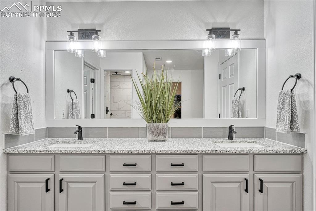 1185 Bowstring Road Monument, CO 80132 - Photo 25 of 46 a bathroom with a granite countertop sink and a mirror