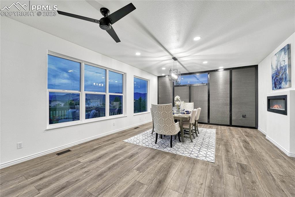 1185 Bowstring Road Monument, CO 80132 - Photo 8 of 46 a dining room with wooden floor a chandelier fan a glass table and chairs