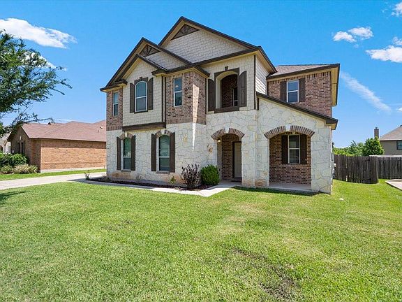 904 Lonesome Lilly Way Pflugerville, TX 78660 - Photo 3 of 34 The property features a two-story exterior with a blend of brick and stone masonry, decorative window shutters, and a well-maintained front lawn