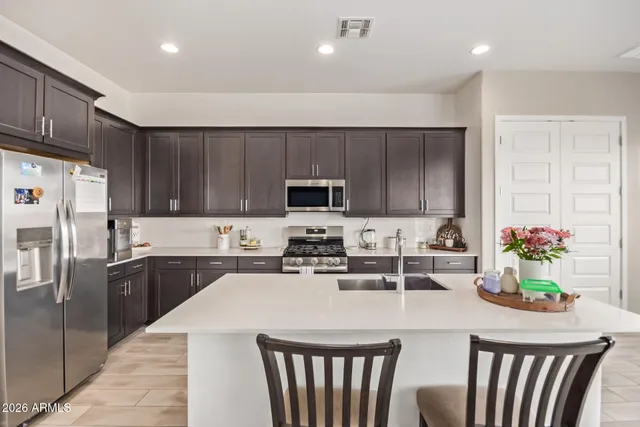 a kitchen with kitchen island granite countertop a stove a sink a microwave and wooden cabinets