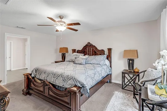 a bedroom with a bed a chair and potted plant on the dresser
