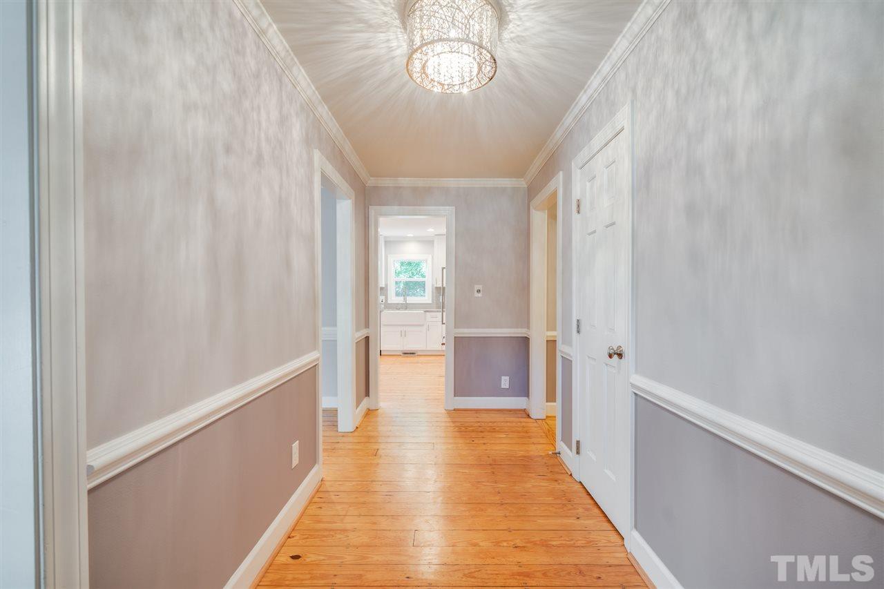 2116 Quail Ridge Road Raleigh, NC 27609 - Photo 3 of 30 a view of a hallway with wooden floor and a chandelier