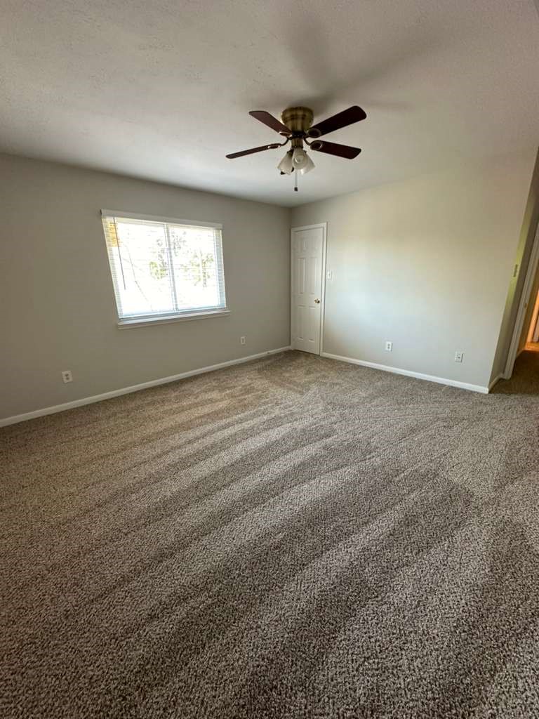 9210 Memorial Grove Drive Spring, TX 77379 - Photo 19 of 23 Room 1 offers a bright and inviting space with plush carpeting, a stylish ceiling fan, and ample natural light streaming through a large window, perfect for relaxation or productivity.