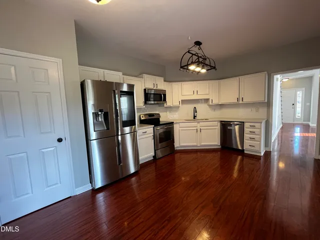 a kitchen with stainless steel appliances granite countertop a refrigerator a stove top oven a sink and dishwasher with wooden floor