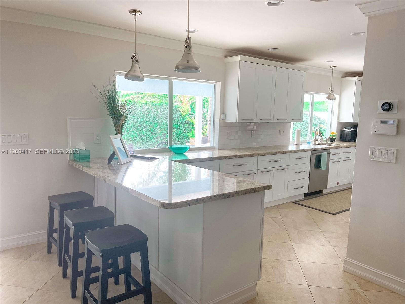 2932 Northeast 36th Street Lighthouse Point, FL 33064 - Photo 5 of 34 a kitchen with a stove a sink a window and chairs