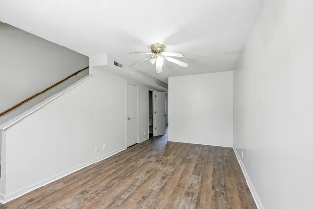 a view of a room with wooden floor and a ceiling fan