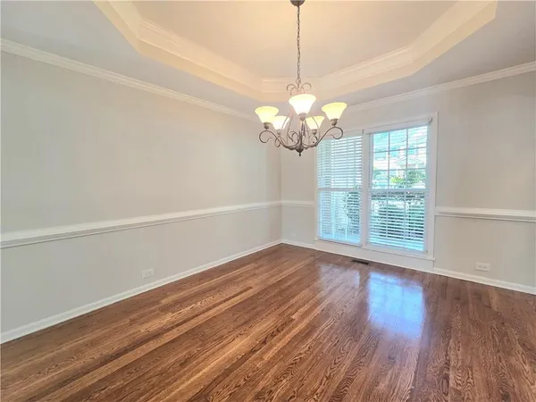 a view of a room with wooden floor chandelier and a window