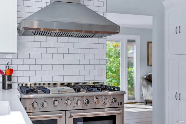 a view of a backyard with table and chairs potted plants and a large tree