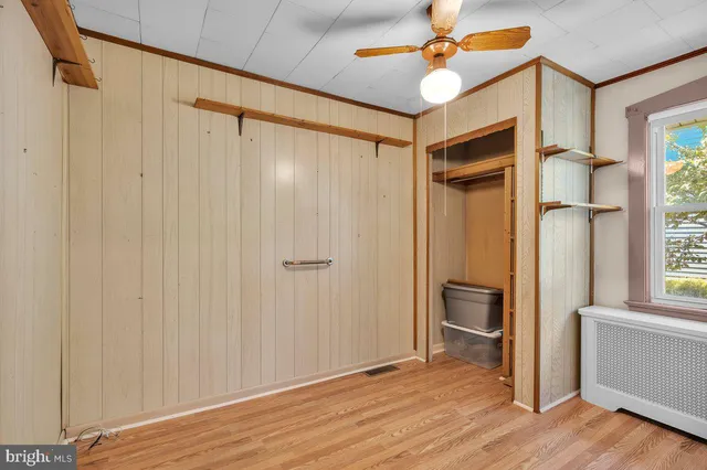 a view of empty room with wooden floor and fan