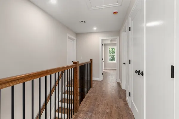 a view of a hallway with wooden floor and a bathroom
