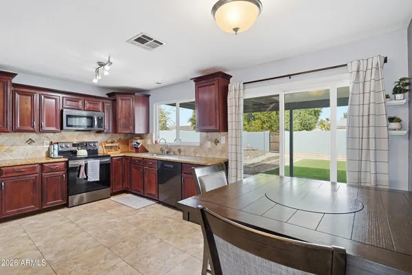 a kitchen with stainless steel appliances granite countertop a stove a sink dishwasher a microwave oven and a dining table with wooden cabinet
