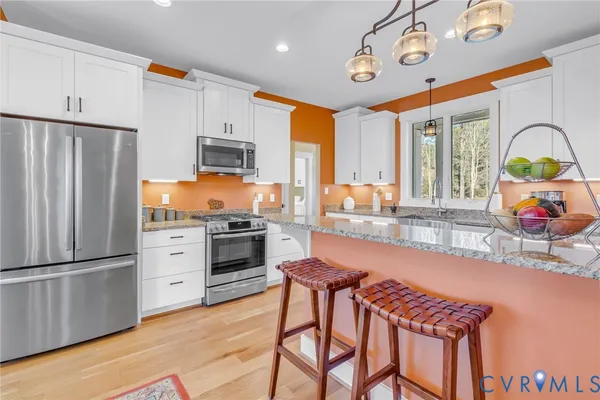 a kitchen with stainless steel appliances granite countertop a stove a refrigerator and a refrigerator with wooden floor