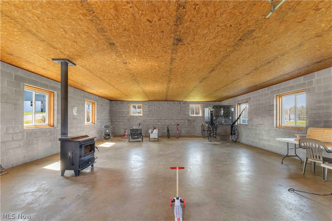 16236 Old State Road Middlefield, OH 44062 - Photo 20 of 33 Misc room with concrete block wall, a wood stove, plenty of natural light, and finished concrete floors