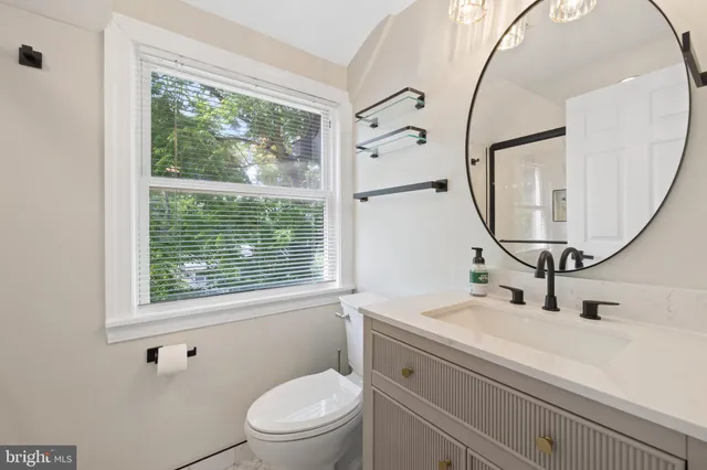 a bathroom with a sink a mirror a vanity and a toilet