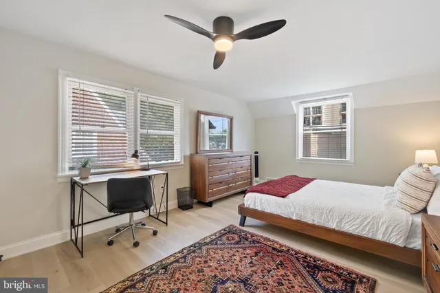 a bedroom with a bed a desk and chair with wooden floor