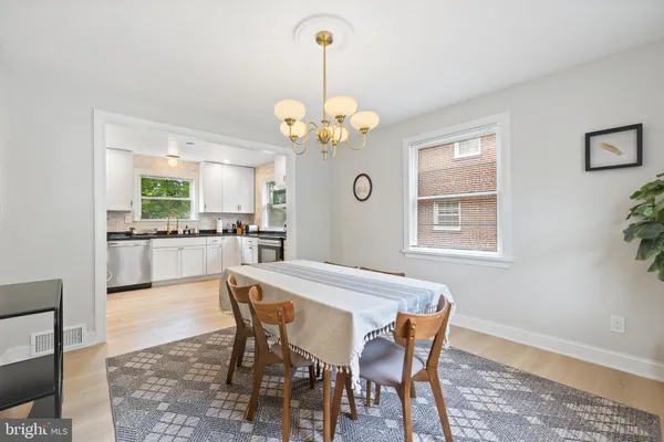 a dining room with wooden floor a chandelier a wooden table and chairs
