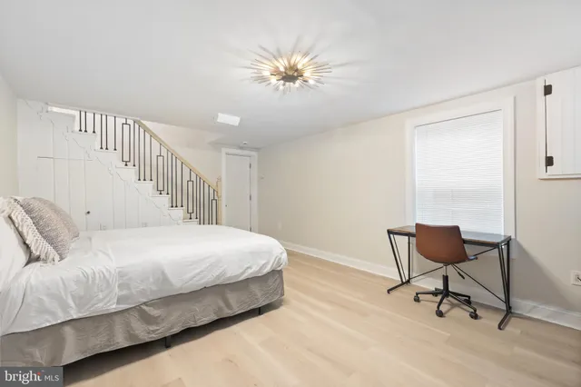 a bedroom with a bed a chair and potted plant on the dresser