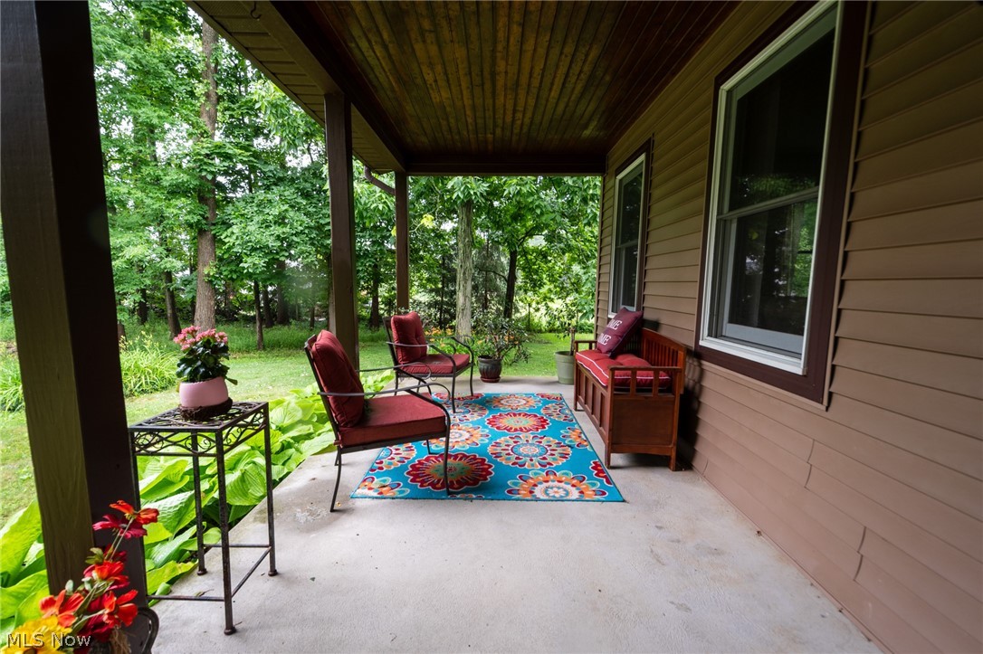 14027 Mayfield Road Huntsburg, OH 44046 - Photo 38 of 50 Covered porch featuring a concrete floor, wood-finish ceiling, and brown siding