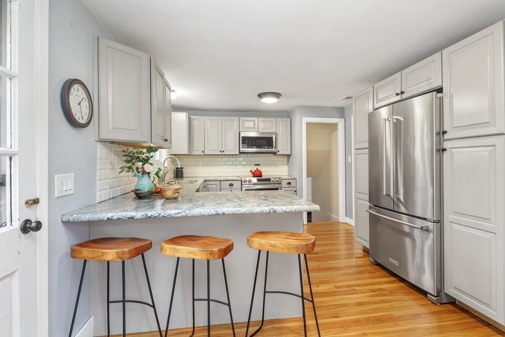 10 Colonial Road Hingham, MA 02043 - Photo 7 of 21 a kitchen with stainless steel appliances granite countertop a refrigerator a stove a sink and a dining table with wooden floor