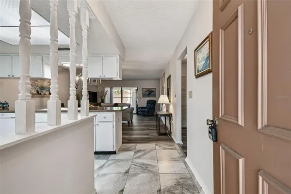 a living room with furniture kitchen view and a wooden floor