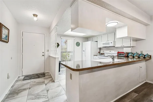 a view of a dining room and livingroom with furniture wooden floor a rug a painting and a chandelier