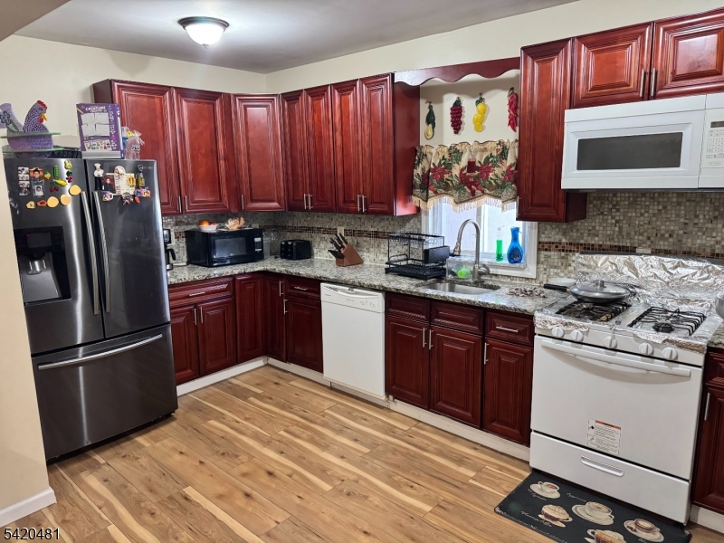 65 Stone Street Newark, NJ 07104 - Photo 20 of 37 a kitchen with stainless steel appliances granite countertop a refrigerator stove top oven and sink with wooden cabinets