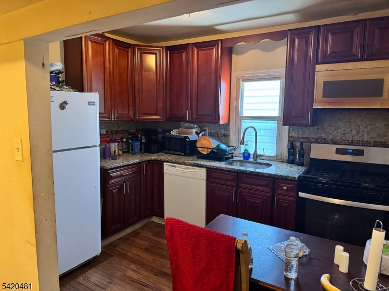 65 Stone Street Newark, NJ 07104 - Photo 10 of 37 a kitchen with stainless steel appliances granite countertop a refrigerator a sink dishwasher and wooden cabinets with a dining table
