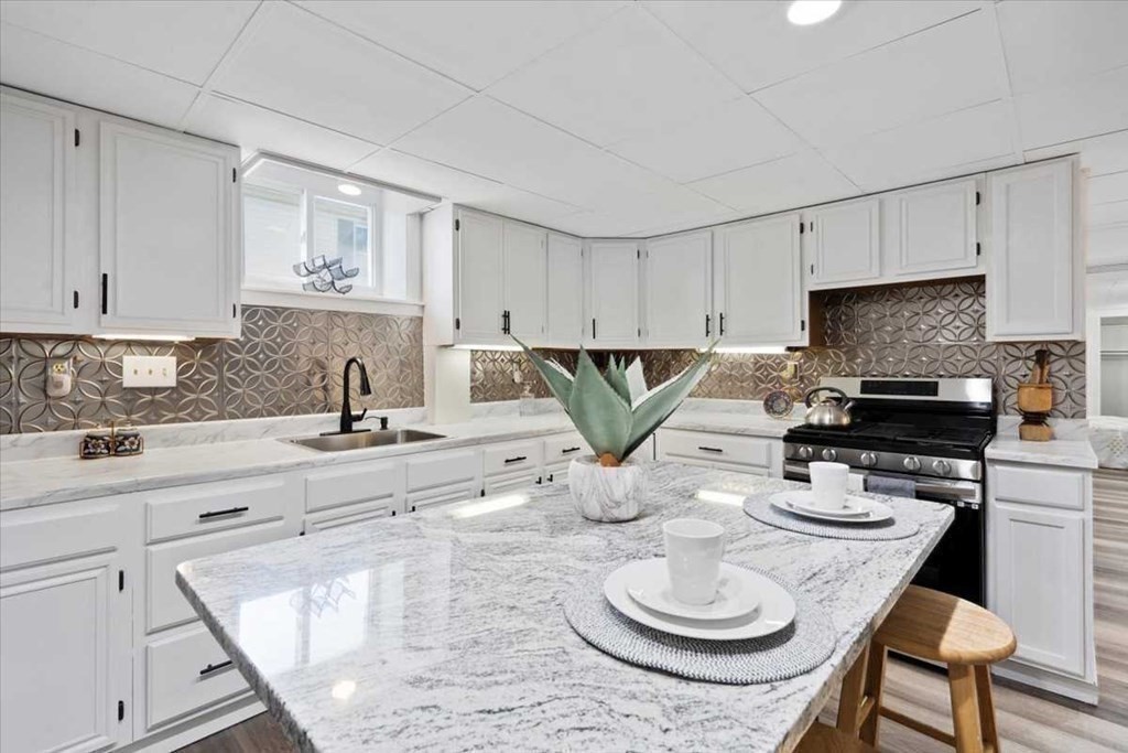 5 Locust Avenue Worcester, MA 01604 - Photo 25 of 40 a kitchen with stainless steel appliances granite countertop a sink a stove a dining table and chairs with wooden floor