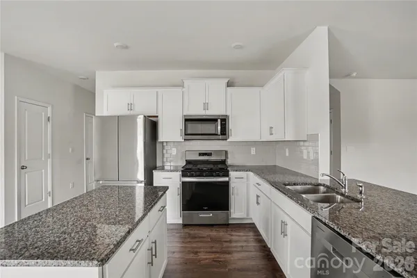 a kitchen with a sink a stove a refrigerator and white cabinets