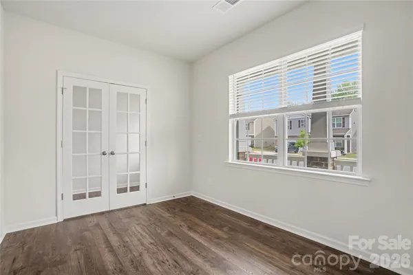an empty room with wooden floor and windows
