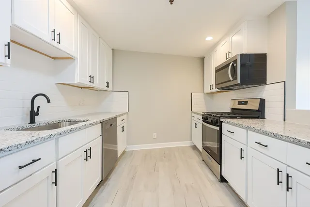 a kitchen with stainless steel appliances granite countertop a sink dishwasher stove and microwave with wooden floor