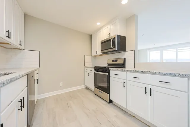 a kitchen with white cabinets stainless steel appliances and a sink