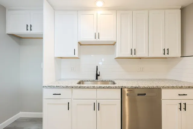 a kitchen with granite countertop white cabinets and a sink