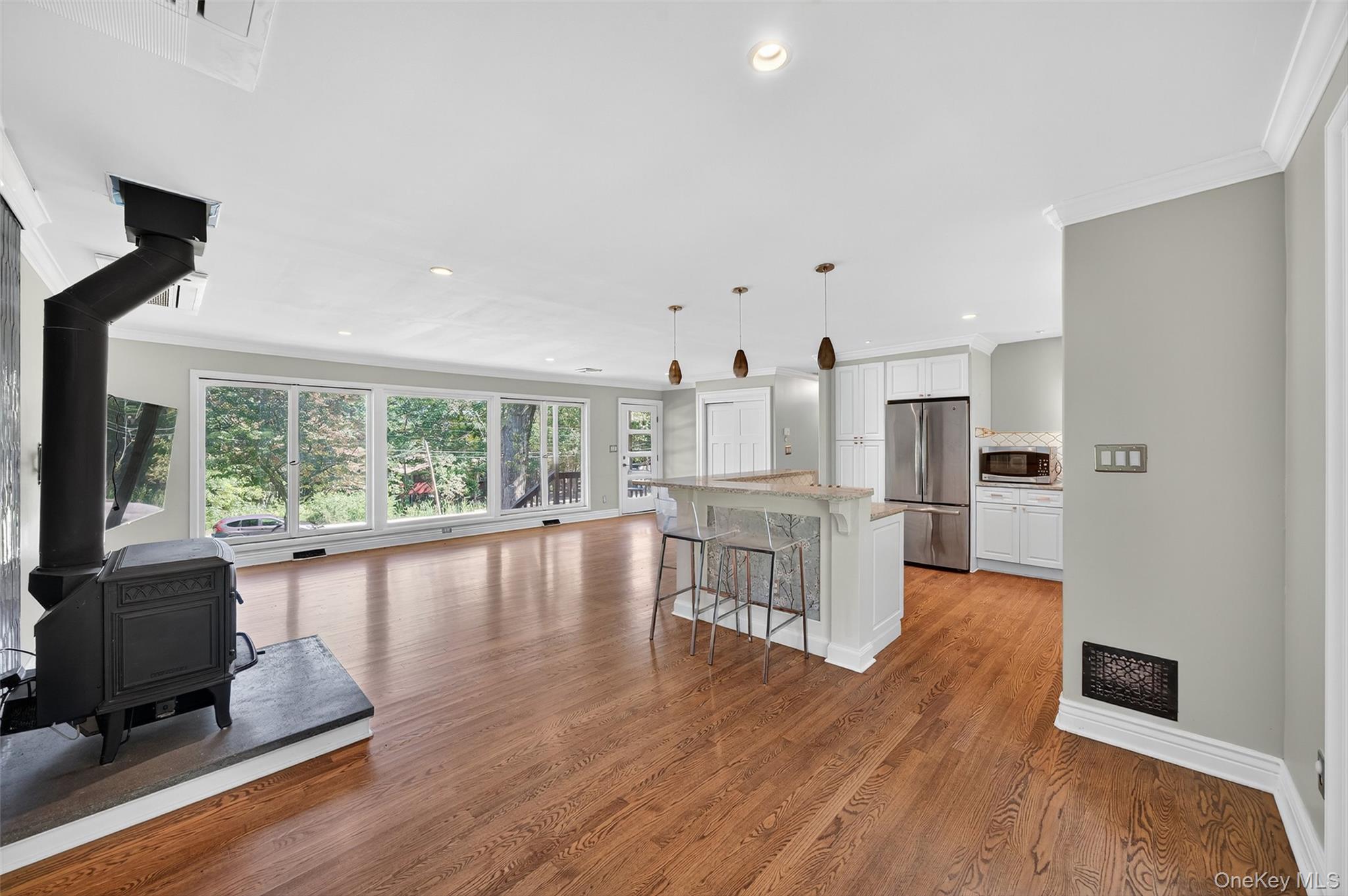 65 Hawxhurst Road Monroe, NY 10950 - Photo 11 of 35 Kitchen featuring a wood stove, a breakfast bar, ornamental molding, white cabinets, and light wood-style floors